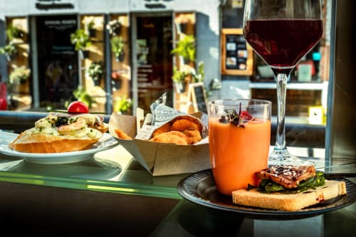 Outdoor tapas and drinks at El Chalecito de Alicante, featuring wine, orange juice, and Spanish appetizers with storefront