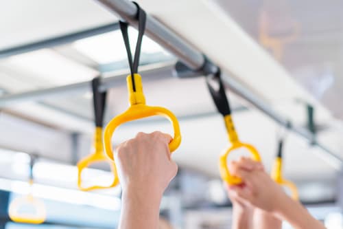 Passenger hand gripping yellow handrail on public transport near El Chalecito de Alicante