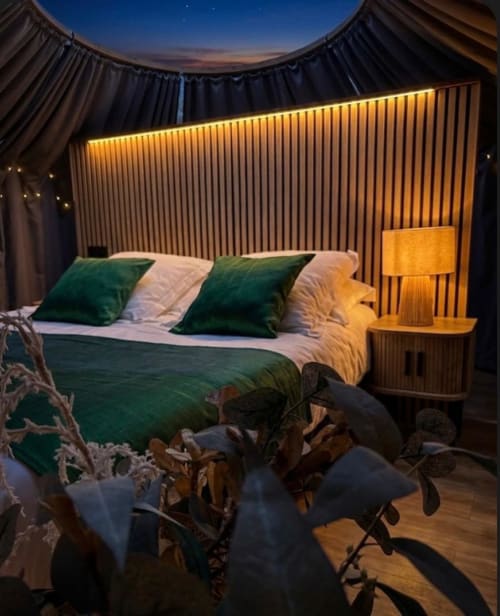 Chambre Bulle Émeraude à Bubble Jade avec lit queen-size, coussins verts, éclairage chaleureux, table de nuit en bois et vue sur le jardin