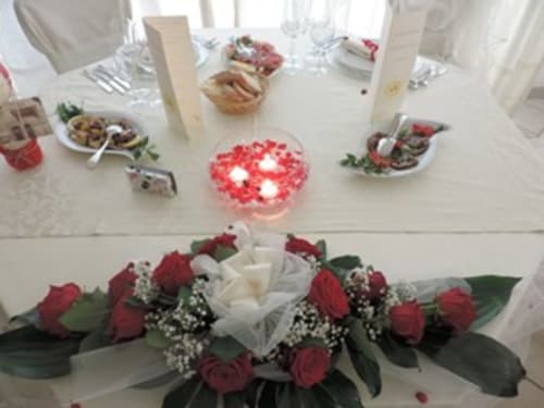 Raffinata mise en place all'Hotel Domu Incantada con rose rosse, candele bianche e coperti per la fine dining a Muravera