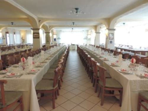 Elegante sala da pranzo dell'Hotel Ristorante Domu Incantada a Muravera con tavoli lunghi, mise en place e luce naturale