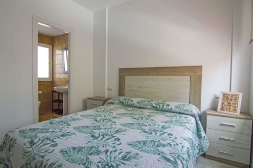 Dormitorio luminoso en la casa rural Casa Doñana de Living Sur, Sanlúcar de Barrameda, con ropa de cama floral verde, cabecero de madera y
