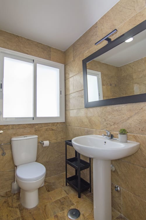 Baño moderno en la cabaña Casa Doñana de Living Sur, Sanlúcar de Barrameda, con lavamanos pedestal, inodoro y espejo enmarcado