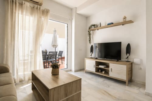 Moderna sala de estar en la casa rural Casa Doñana de Sanlúcar de Barrameda con muebles de madera, TV pantalla plana y acceso a terraza