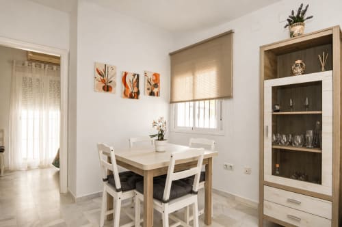 Comedor luminoso en la cabaña Casa Doñana con mesa de madera, sillas blancas y estantería empotrada con cristalería
