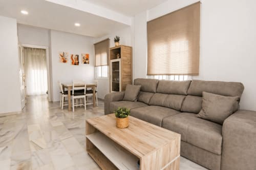 Sala de estar moderna de la casita Casa Doñana en Sanlúcar de Barrameda con sofá gris, mesita de madera y zona de comedor