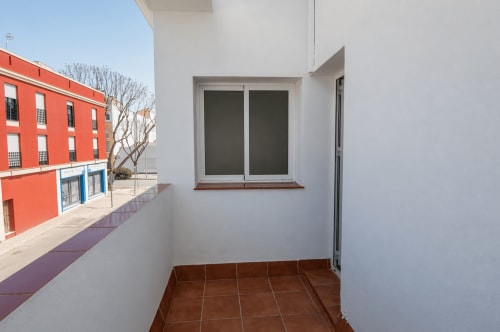 Terraza soleada de la casita Living Sur en Sanlúcar de Barrameda con vistas a la ciudad, azulejos de barro y muros blancos