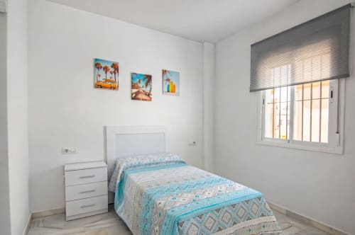 Dormitorio luminoso en la casita Living Sur de Sanlúcar de Barrameda con cama individual, mesilla blanca y decoración temática costera