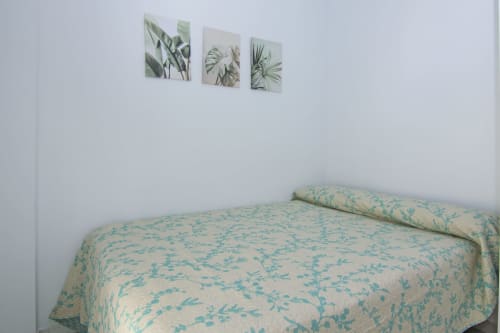 Dormitorio de la casita Casa Doñana en Living Sur, Sanlúcar de Barrameda, con arte botánico en la pared sobre ropa de cama estampada