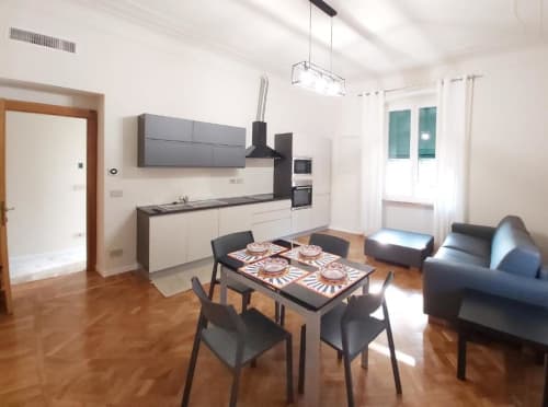 Cucina e salotto open-plan moderno nell'appartamento 4 Le Due Piazze a Genova, con tavolo da pranzo, divano e arredi completi