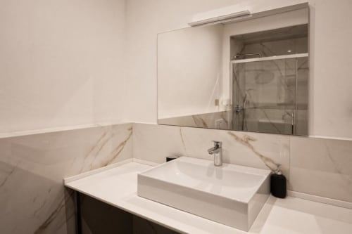Bagno moderno nell'appartamento Le Due Piazze di Genova con lavabo in ceramica bianca, rivestimento in marmo e mobiletto a specchio