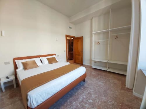 Ampia camera da letto nell'appartamento Le Due Piazze a Genova con letto in legno, armadio bianco e vista sulla città