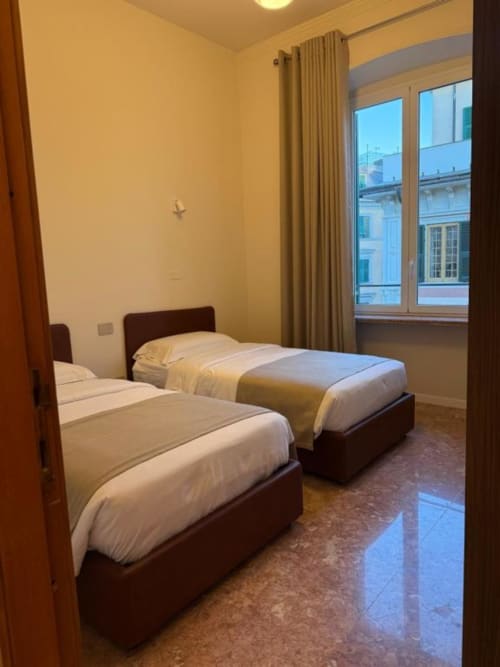 Camera da letto matrimoniale con strutture in legno scuro e biancheria bianca nell'Appartamento Standard a 2 camere di Le Due Piazze BnB, Genova, con vista città