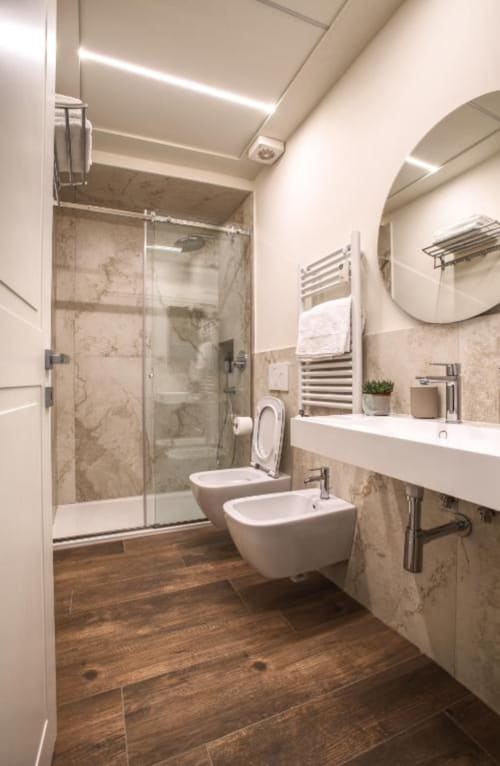 Bagno moderno in Le Due Piazze Genova con piastrelle in marmo, doppi lavabi, WC, bidet e doccia con box in vetro