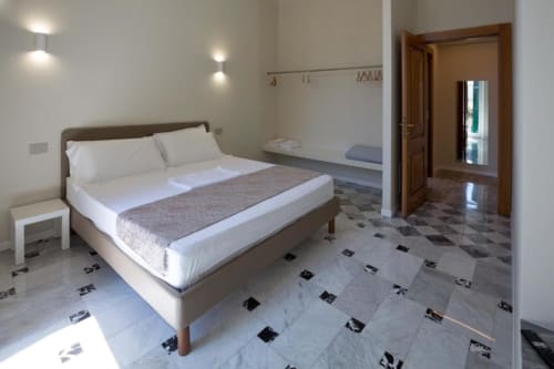 Camera moderna nell'appartamento Le Due Piazze a Genova con letto matrimoniale, biancheria bianca, pavimento in marmo e porta del bagno ensuite
