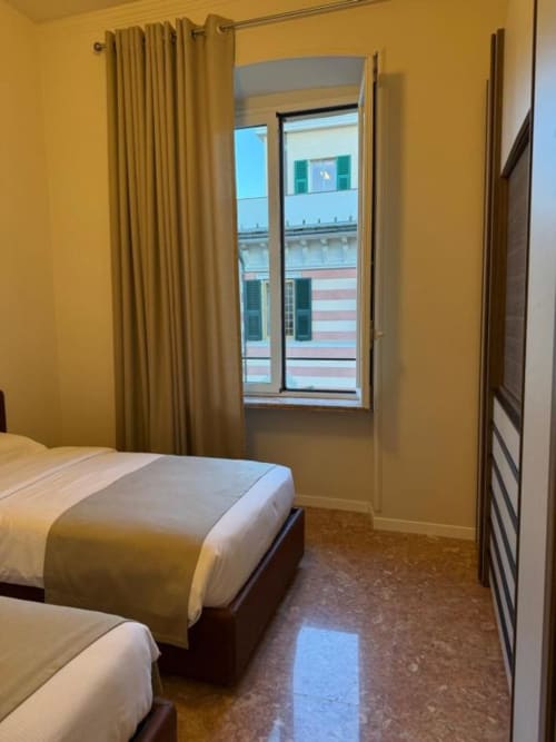 Camera da letto gialla brillante a Le Due Piazze, Genova con letti gemelli, ampie finestre con vista sull'architettura urbana e design moderno
