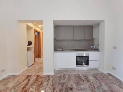 Cucina moderna con mobili bianchi, piano di lavoro grigio e forno incorporato nell'appartamento Le Due Piazze a Genova