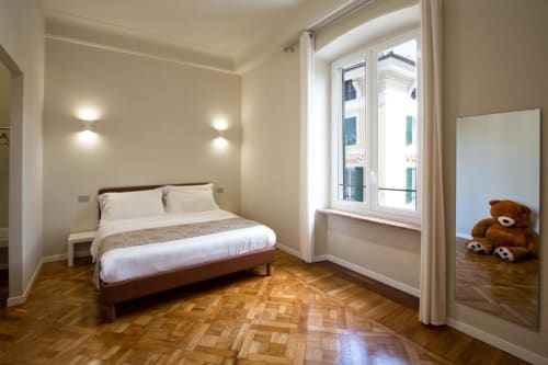 Camera luminosa a Le Due Piazze a Genova con letto queen, parquet, balcone con vista città e illuminazione moderna
