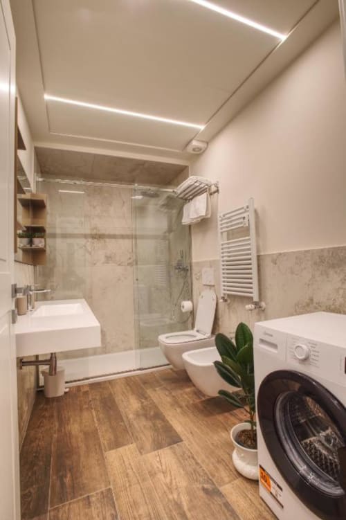 Bagno moderno dell'appartamento Le Due Piazze Genova con doccia, WC, lavatrice e pavimentazione in legno