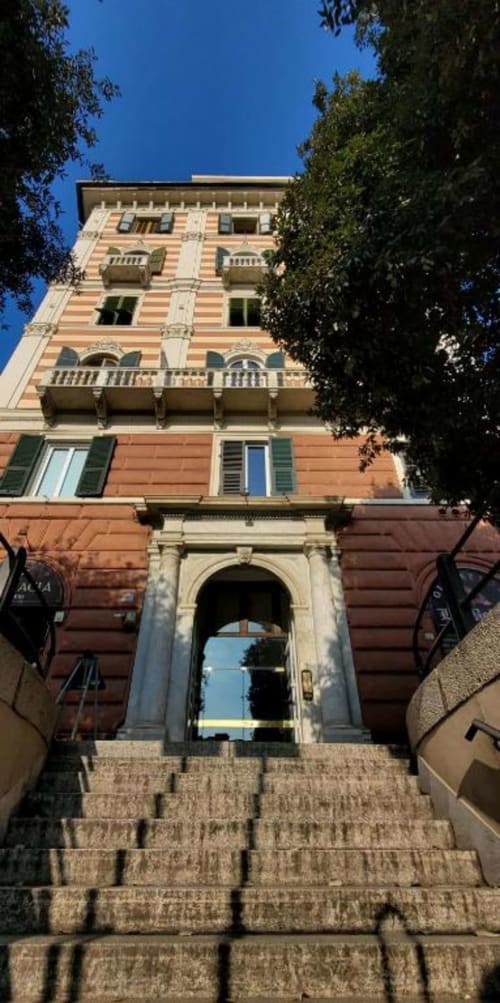 Storica facciata in terracotta dell'edificio Le Due Piazze a Genova con ingresso ad arco e muri ricoperti di edera