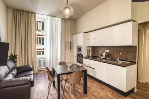 Cucina-soggiorno moderno a Genova con mobili bianchi, top scuri e zona living in Le Due Piazze
