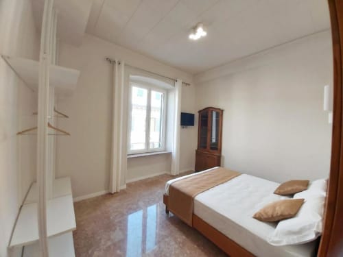Camera luminosa dell'appartamento Le Due Piazze a Genova con letto matrimoniale, finestra con vista sulla città, armadio in legno e marmo