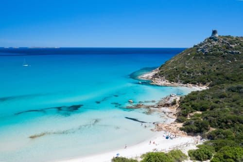 Turquoise beach cove with white sand and tower ruin near Hotel Domu Incantada in Muravera, Sardinia