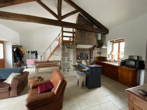 Spacieux séjour du Domaine de Beau Site avec poutres apparentes, cheminée et vue sur le jardin