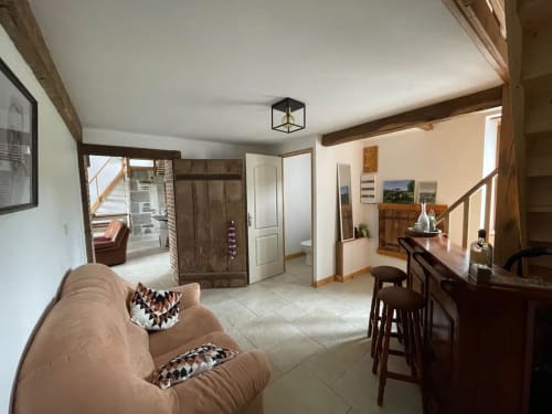 Spacieux séjour du Domaine de Beau Site avec canapé beige, poutres en bois et vue sur le jardin à Peyrat-de-Bellac