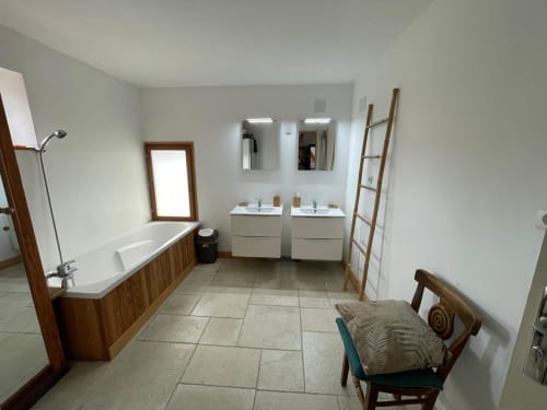 Salle de bains spacieuse du gîte Domaine de Beau Site avec deux lavabos, baignoire et sèche-serviettes chauffant
