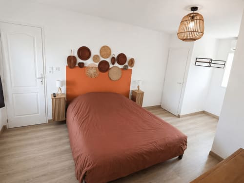Modern bedroom at Domaine de Beau Site with orange headboard, terracotta bedding, woven decor, and garden views