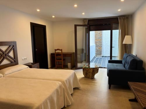 Spacious hotel room at Hotel Mulhacén Trevélez with twin beds, balcony, and modern furnishings overlooking Granada