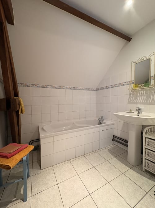 Bright bathroom at Ferme de la Forterie with white tile walls, bathtub, pedestal sink, and heated towel rack in Verlinghem,