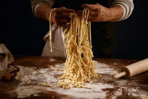 Chef hands holding fresh pasta at Haven Spa Luxury Loft in Como, Italy, showing authentic Italian culinary traditions