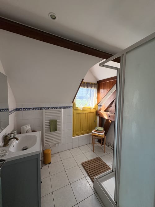 Salle de bains spacieuse de la chambre La Verveine à la Ferme de la Forterie Verlinghem, avec carrelage blanc, lavabo, douche et