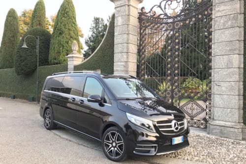 Black Mercedes van parked at ornate gate of Haven Spa Luxury Loft in Como, Italy, with cypress trees and formal estate