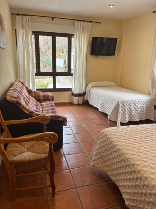 Spacious hotel room at Hotel Mulhacén Trevélez with two beds, wooden furniture, terracotta flooring, and mountain views