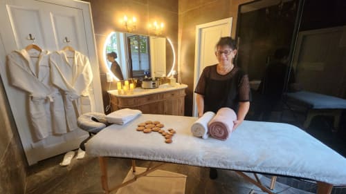 Spa attendant displays bathrobes and rolled towels at Château de la Rochetière B&B in Marcilloles, France