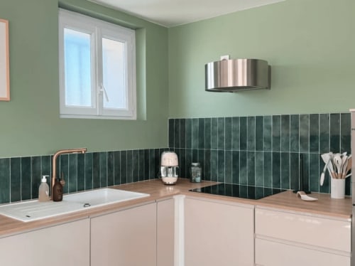 Salle de bain moderne de la villa ARLOÉ avec carrelage vert, plan de travail en bois, lavabo blanc et hotte inox à La