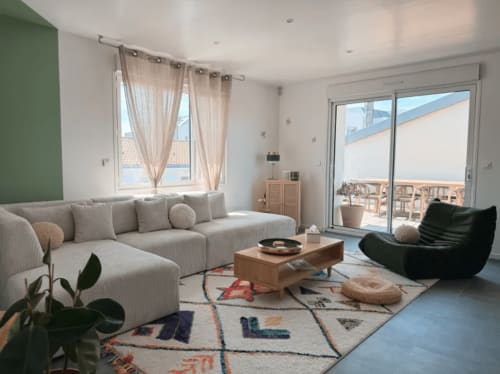Villa moderne à La Rochelle avec canapé sectionnel beige, fauteuil noir, table en bois et vue sur la terrasse