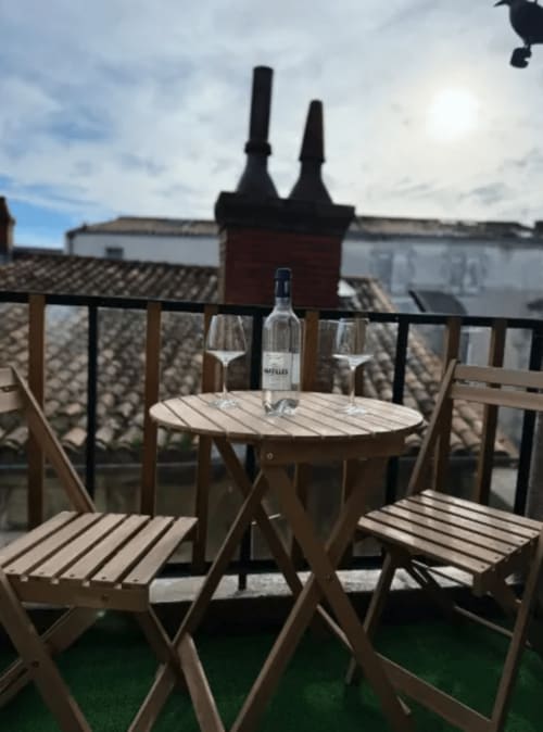Terrasse panoramique ARLOÉ La Rochelle avec verres de vin, bouteille et mobilier en bois dominant les cheminées historiques