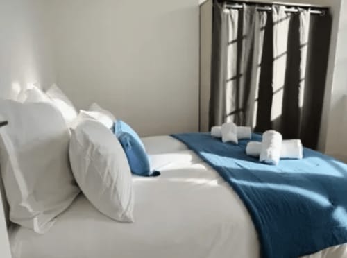 Chambre lumineuse avec lits jumeaux, accents bleus et oreillers blancs à l'appartement ARLOÉ à La Rochelle