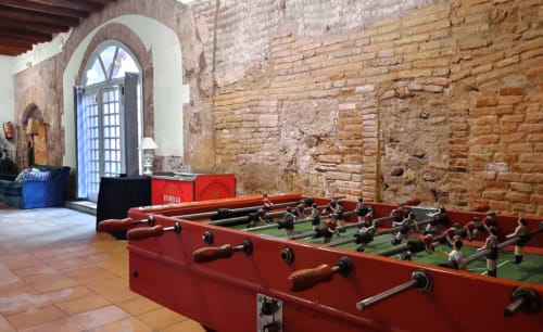 Mesa de futbolín roja en sala de ladrillo rústico del Hotel Restaurante Can Carol, Capellades, España
