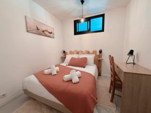Chambre douillette à l'ARLOÉ à La Rochelle avec literie terracotta, lit en bois et fenêtre lumineuse