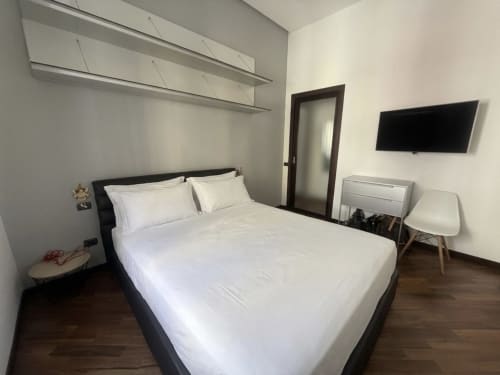 Camera moderna presso ROOMITO APARTMENTS Napoli con letto queen, TV a schermo piatto, pavimento in legno e arredi contemporanei