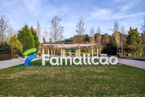 Cartel de Famalicão en la entrada del parque Quinta Das Pirâmides con columnas blancas y jardines verdes en Vila Nova de Famalicão