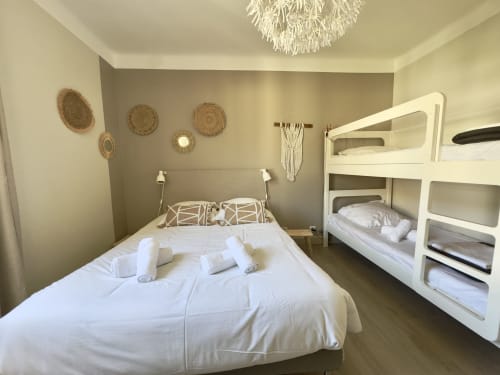 Chambre lumineuse avec lit double et lits superposés blancs à l'appartement SoleMare à Alata, décor côtier et moderne