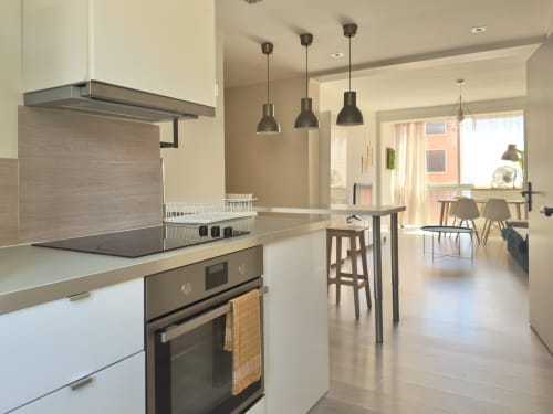 Cuisine moderne et séjour ouverts dans l'appartement L'Ajax à Alata, équipés d'électroménagers en inox, luminaires suspendus
