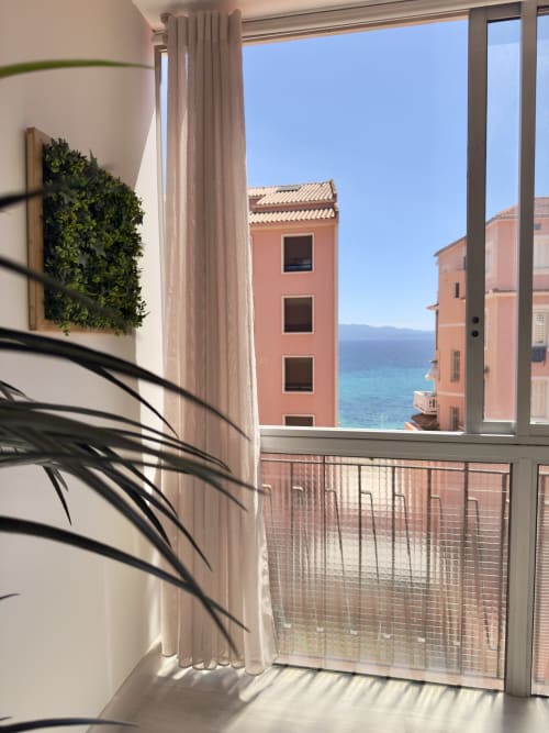 Vue radieuse sur la mer depuis l'appartement L'Ajax à Alata : bâtiments corail, eau turquoise méditerranéenne, plante murale, blanc