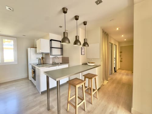 Cuisine ouverte moderne et espace repas au L'Ajax d'Alata avec luminaires suspendus, bar et acier inoxydable